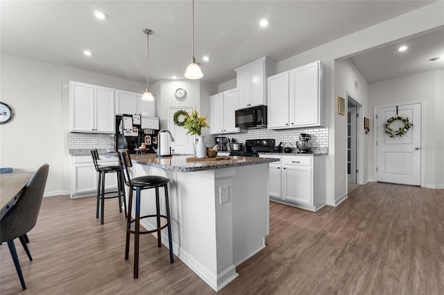 kitchen with wood finished floors, decorative backsplash, a sink, and black appliances