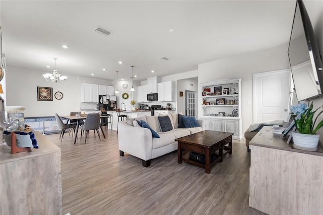 living area with a chandelier, recessed lighting, visible vents, and wood finished floors