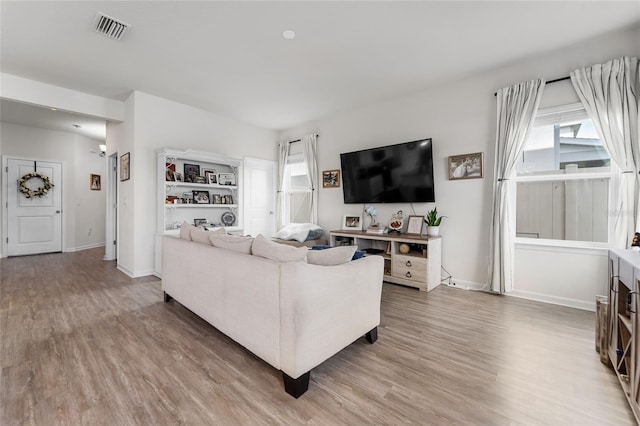 living area featuring light wood-style flooring, baseboards, and visible vents