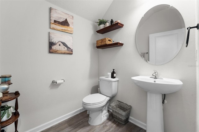 half bath featuring toilet, wood finished floors, and baseboards