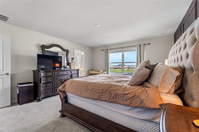 bedroom featuring light carpet, visible vents, and a textured ceiling
