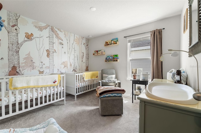 carpeted bedroom featuring a nursery area