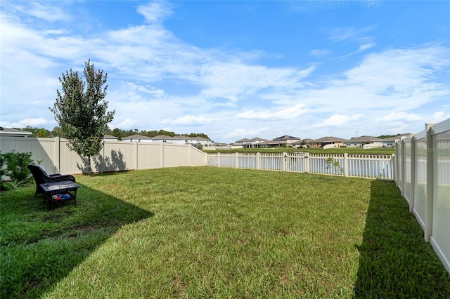 view of yard featuring a fenced backyard, a residential view, and a water view