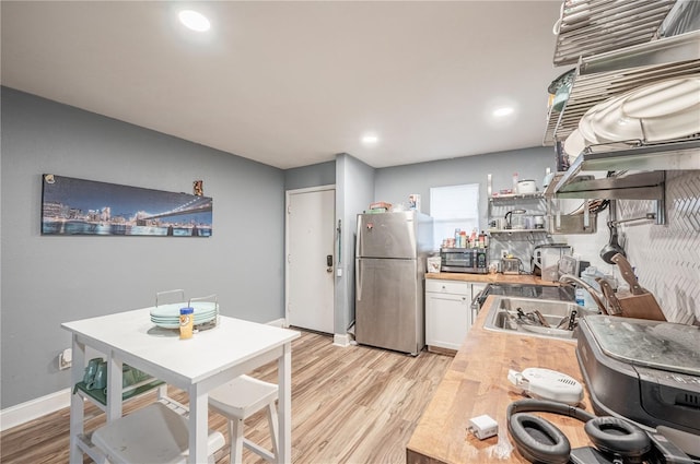 kitchen with open shelves, stainless steel appliances, light wood-style flooring, and a sink