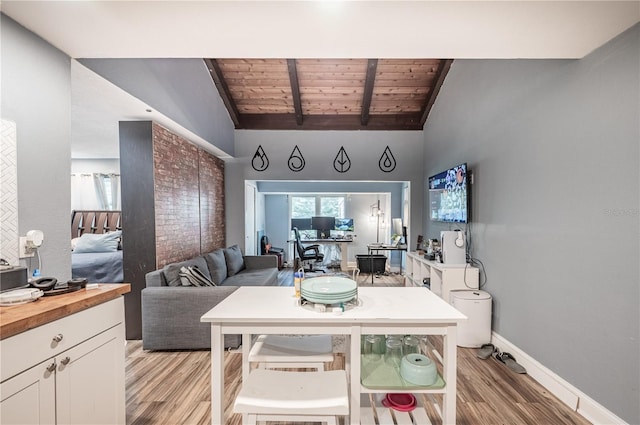 dining room with wood ceiling, vaulted ceiling with beams, and light hardwood / wood-style floors