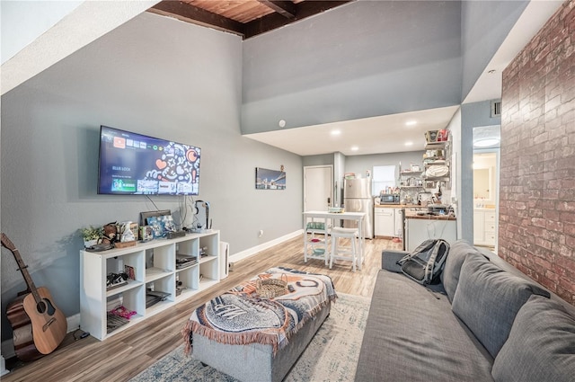 living room featuring brick wall, light hardwood / wood-style flooring, wooden ceiling, and beam ceiling