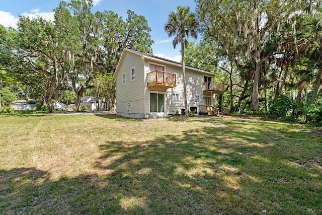 rear view of house featuring a balcony, a yard, and a deck