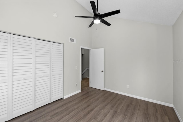 unfurnished bedroom featuring dark wood-type flooring, ceiling fan, high vaulted ceiling, and a closet