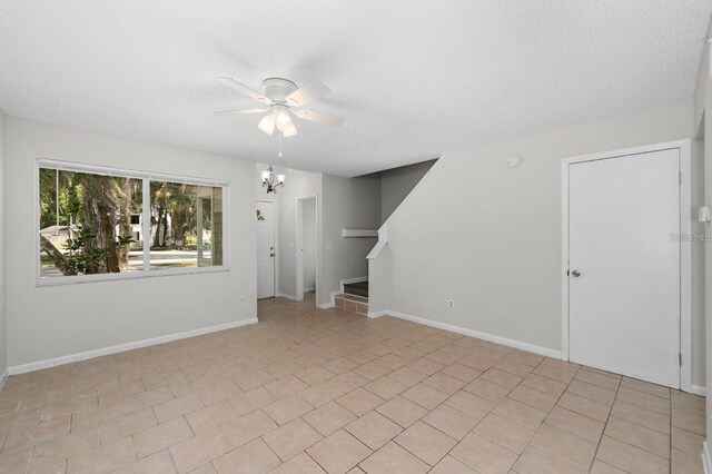 unfurnished living room with ceiling fan, light tile patterned floors, and a textured ceiling