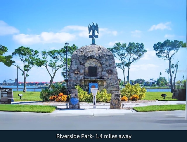 community / neighborhood sign with a lawn and a water view