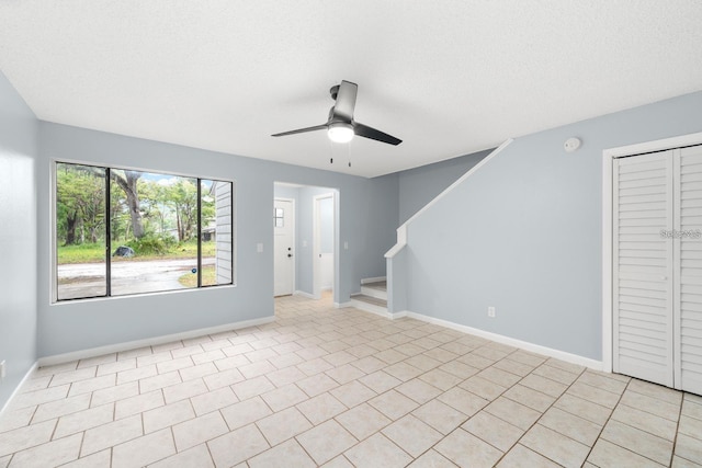 spare room with ceiling fan, light tile patterned floors, and a textured ceiling