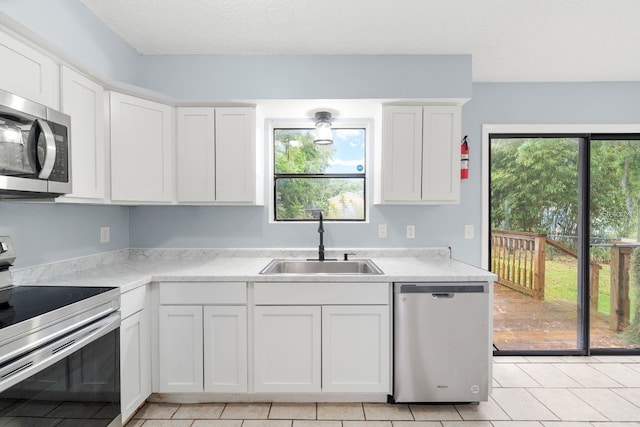 kitchen with white cabinetry, stainless steel appliances, light tile patterned flooring, and sink