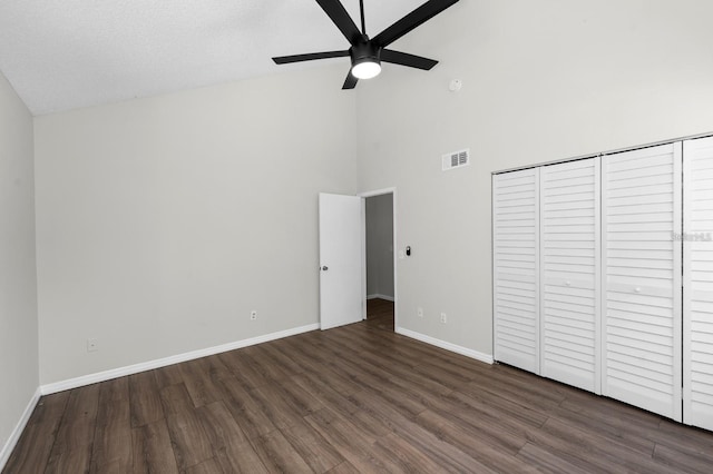 unfurnished bedroom with dark wood-type flooring, ceiling fan, and high vaulted ceiling