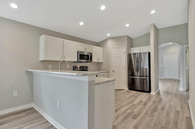 kitchen with stainless steel appliances, light stone countertops, kitchen peninsula, and vaulted ceiling