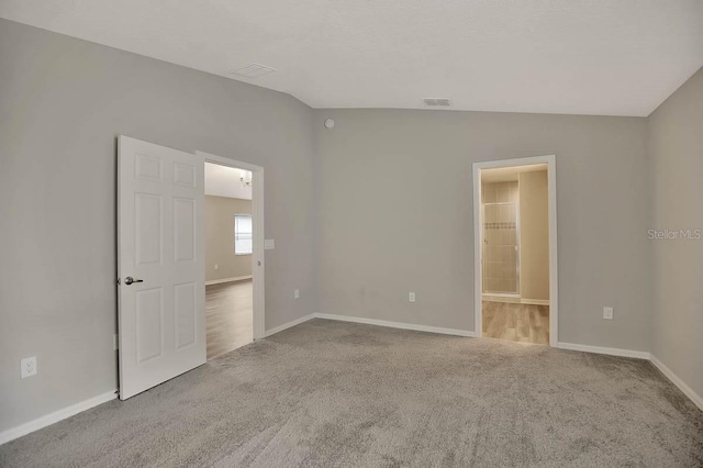 carpeted spare room with lofted ceiling