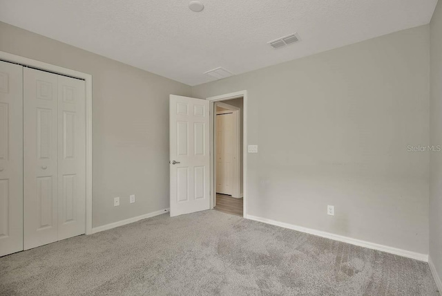 unfurnished bedroom featuring a textured ceiling, carpet flooring, and a closet