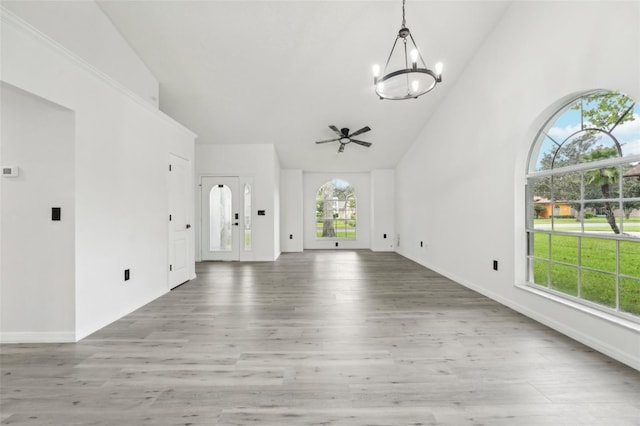 unfurnished living room featuring ceiling fan with notable chandelier, hardwood / wood-style floors, and high vaulted ceiling