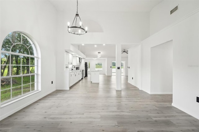 foyer with a high ceiling, sink, a chandelier, and light wood-type flooring