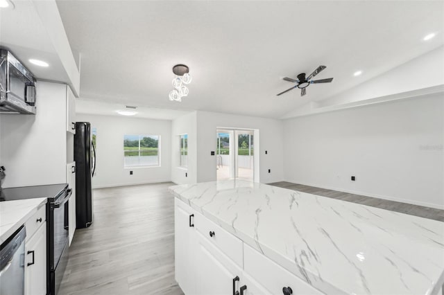 kitchen featuring white cabinetry, light stone counters, vaulted ceiling, light hardwood / wood-style flooring, and stainless steel appliances