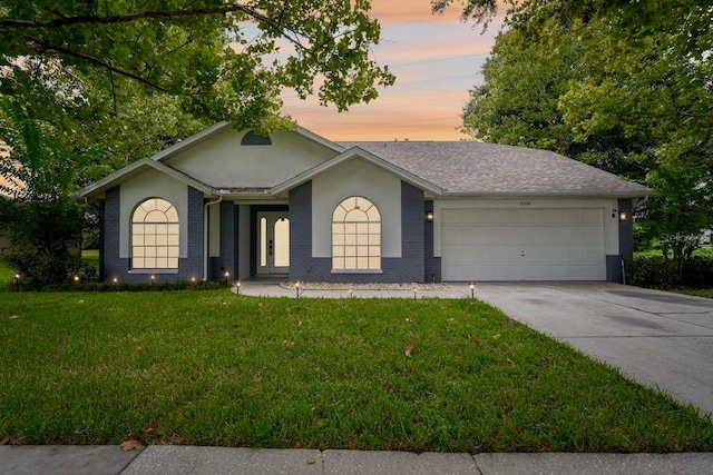 ranch-style home featuring a garage and a yard