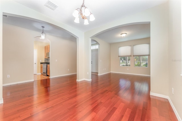 unfurnished living room with hardwood / wood-style floors and a notable chandelier