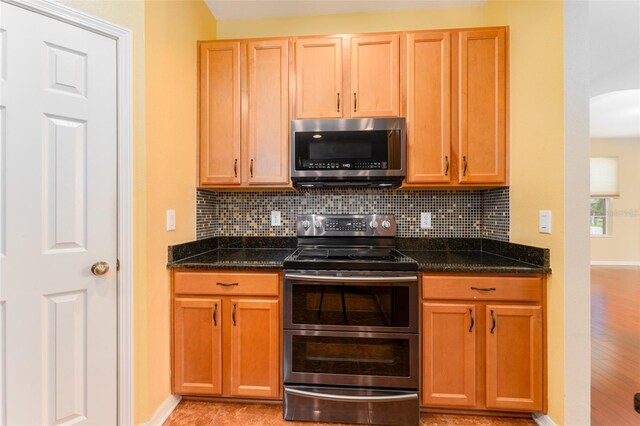 kitchen featuring dark stone counters, stainless steel appliances, light hardwood / wood-style floors, and tasteful backsplash