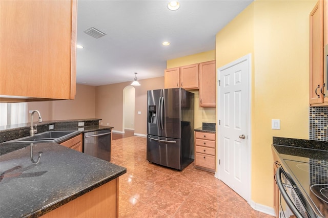 kitchen with dark stone counters, pendant lighting, light tile patterned floors, stainless steel appliances, and sink