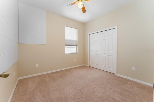 unfurnished bedroom with light carpet, ceiling fan, and a closet