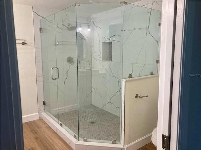 bathroom with a shower with shower door, toilet, and hardwood / wood-style flooring