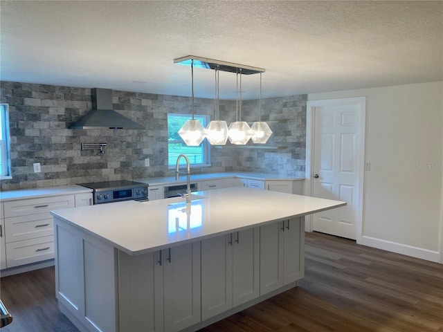 kitchen with a kitchen island with sink, white cabinets, and wall chimney range hood