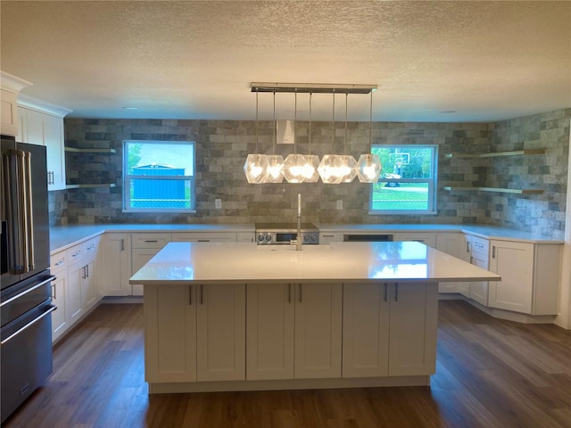 kitchen with pendant lighting, an island with sink, dark hardwood / wood-style floors, and high end refrigerator