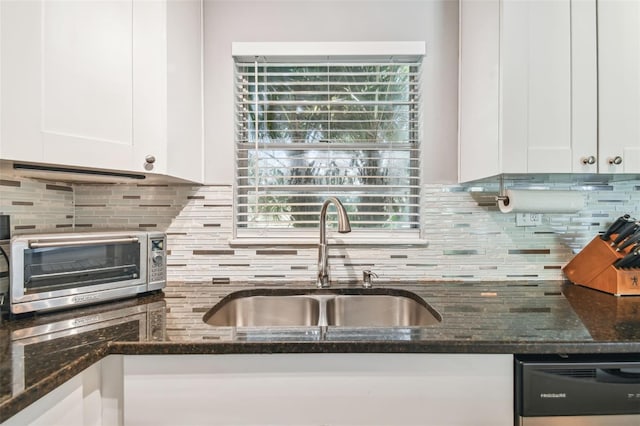 kitchen with sink, white cabinetry, dishwasher, and dark stone countertops