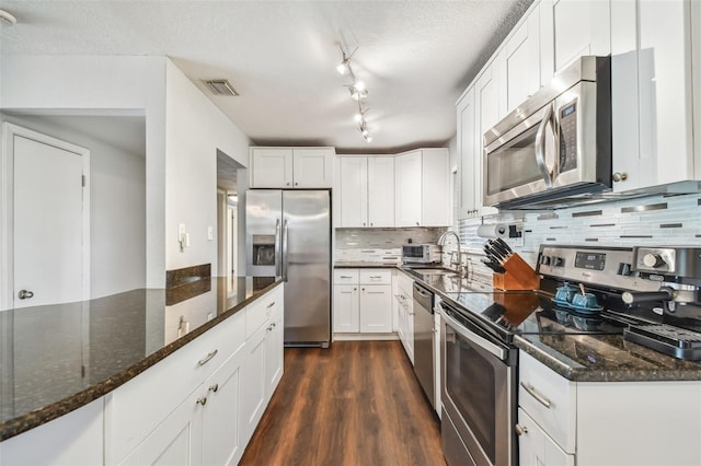 kitchen featuring white cabinetry, stainless steel appliances, dark wood-type flooring, and dark stone countertops