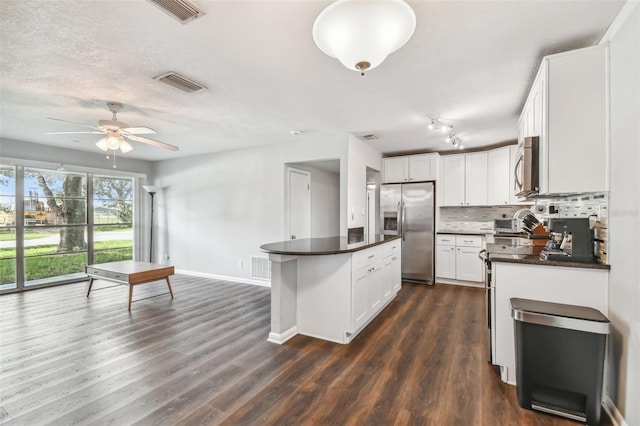 kitchen featuring decorative backsplash, dark hardwood / wood-style flooring, appliances with stainless steel finishes, white cabinetry, and a center island