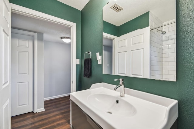 bathroom featuring a tile shower, a textured ceiling, hardwood / wood-style flooring, and vanity