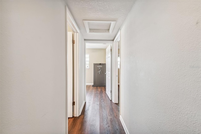 hall featuring dark wood-type flooring and a textured ceiling