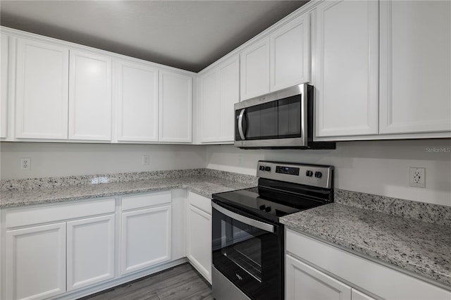 kitchen with dark hardwood / wood-style flooring, light stone countertops, stainless steel appliances, and white cabinets