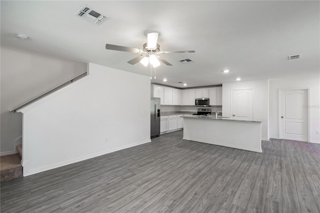 kitchen featuring appliances with stainless steel finishes, hardwood / wood-style floors, an island with sink, and white cabinets