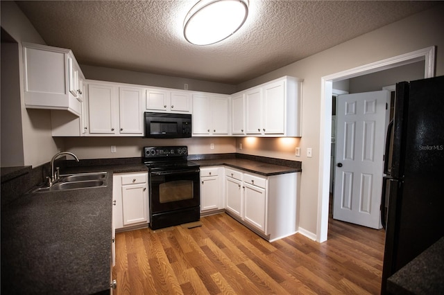 kitchen with black appliances, sink, hardwood / wood-style floors, and white cabinets