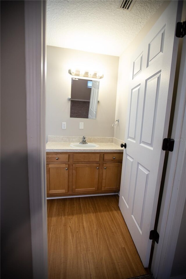 bathroom with vanity, a textured ceiling, and wood-type flooring