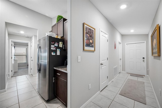 hallway featuring vaulted ceiling and light tile patterned flooring