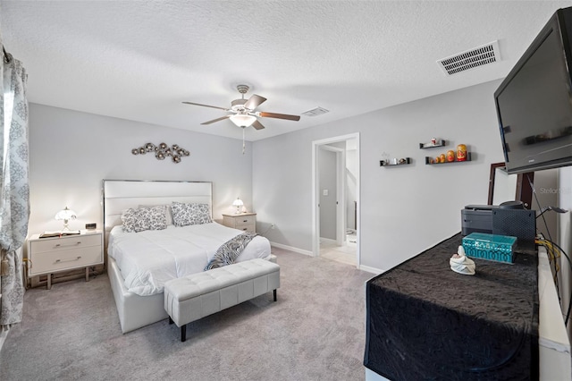 bedroom featuring light colored carpet, ceiling fan, and a textured ceiling