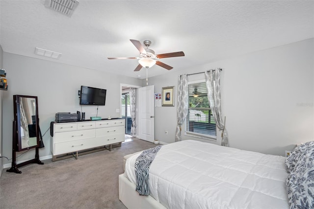 bedroom featuring light carpet, a textured ceiling, and ceiling fan