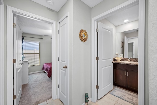 hallway with light tile patterned floors, a textured ceiling, and sink