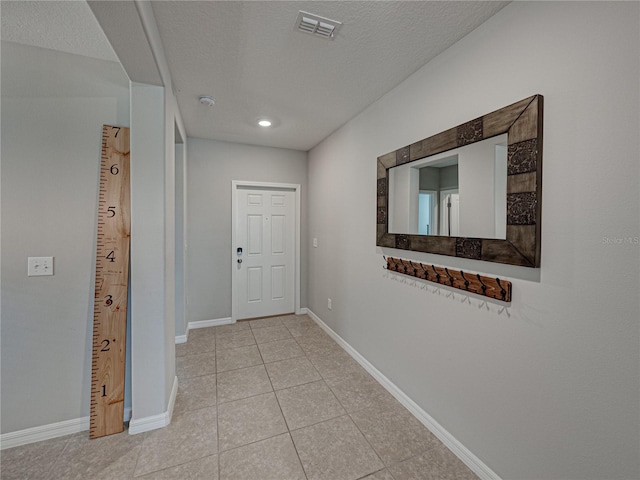 foyer entrance featuring a textured ceiling and light tile patterned flooring