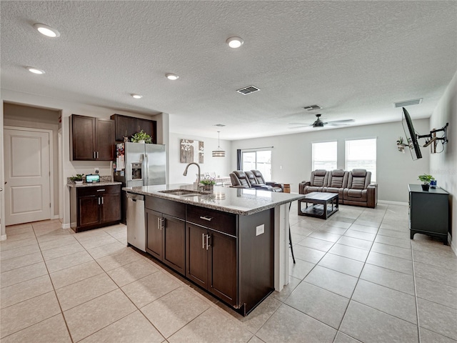 kitchen featuring a kitchen island with sink, pendant lighting, stainless steel appliances, sink, and ceiling fan