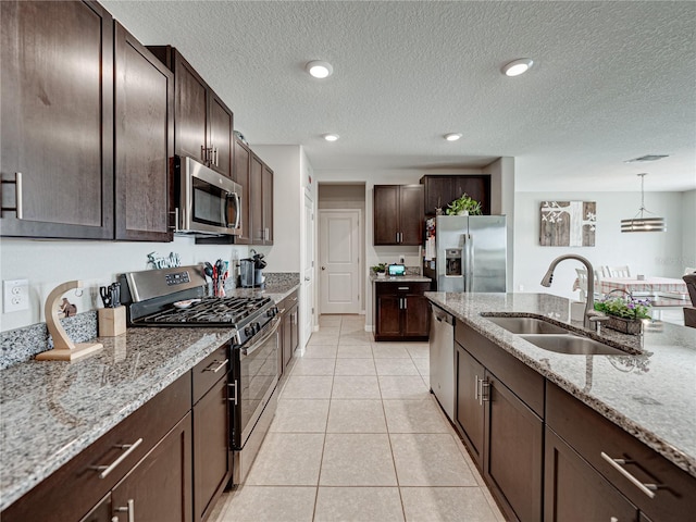 kitchen featuring decorative light fixtures, light stone countertops, light tile patterned floors, appliances with stainless steel finishes, and sink