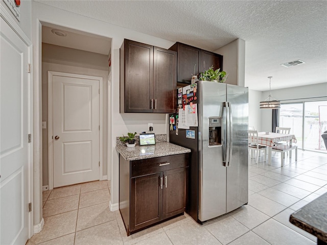 kitchen with light tile patterned flooring, hanging light fixtures, dark brown cabinetry, and stainless steel refrigerator with ice dispenser