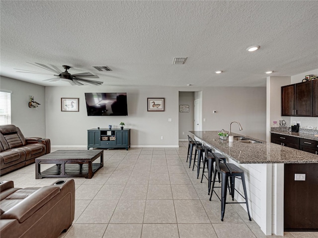 tiled living room with ceiling fan, a textured ceiling, and sink