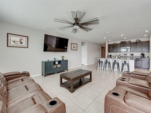 tiled living room featuring a textured ceiling, sink, and ceiling fan